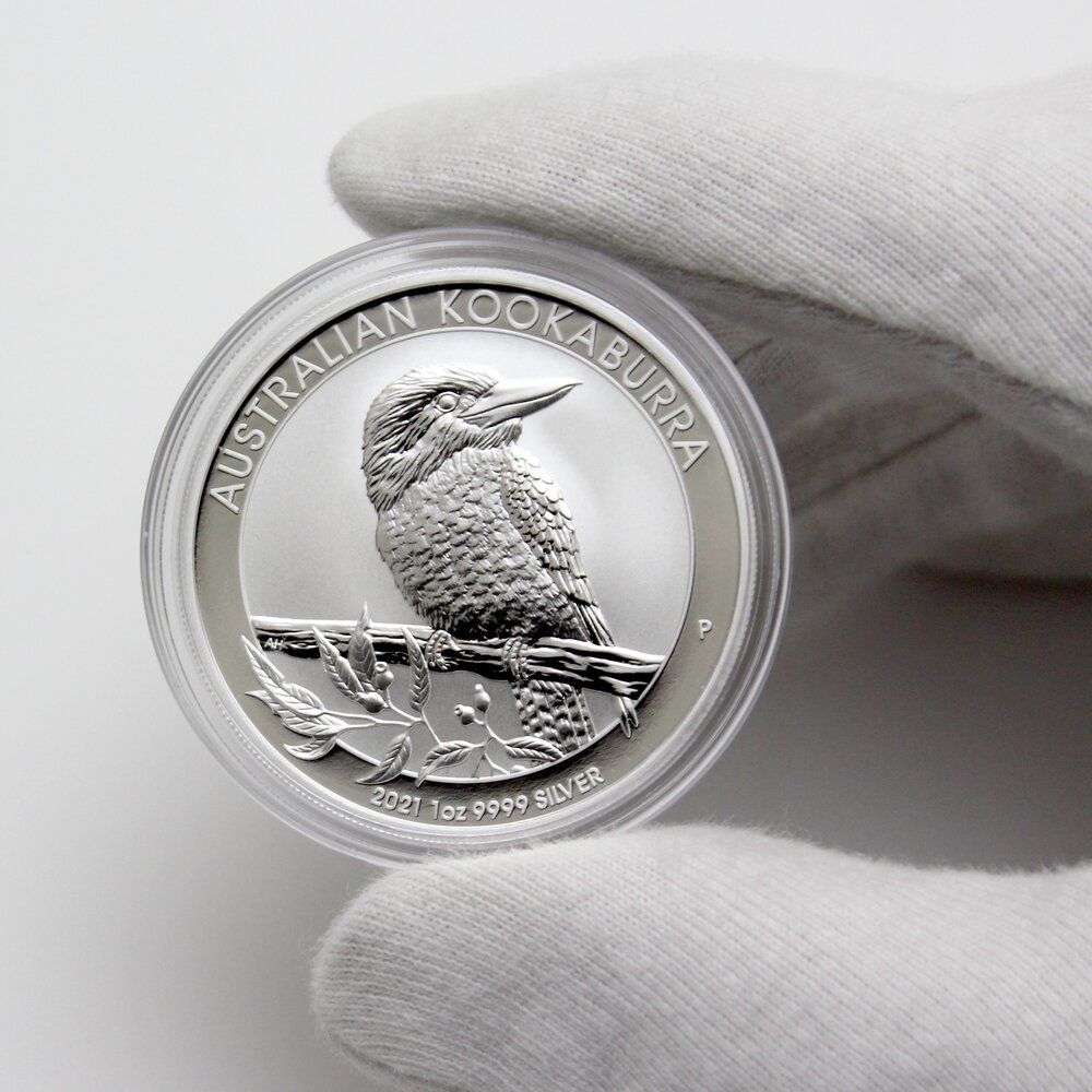 Closeup of a gloved hand holding an Australian Kookaburra silver coin.