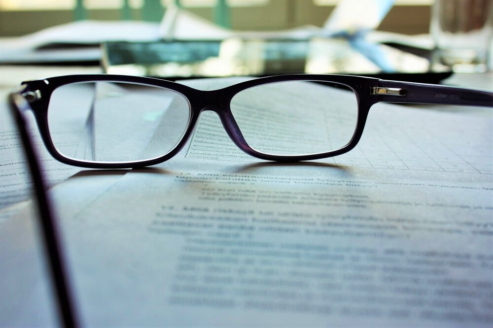 A pair of glasses sitting on a pile of financial documents.